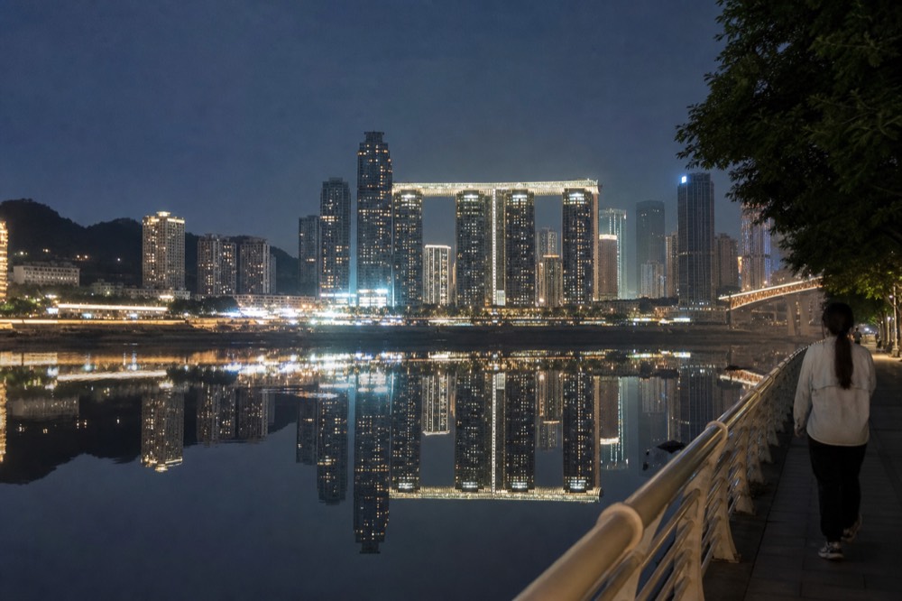 Rows of glowing high-rise towers reflected in a calm river at night