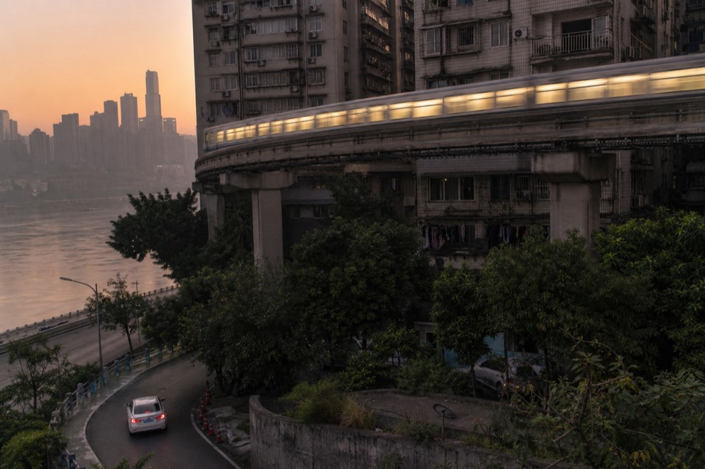 Elevated rail viaduct curving between tall apartment towers in the evening