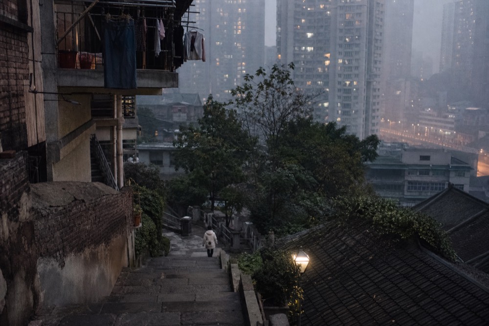 Steep pedestrian stairway climbing between tall residential towers on a hillside in the evening