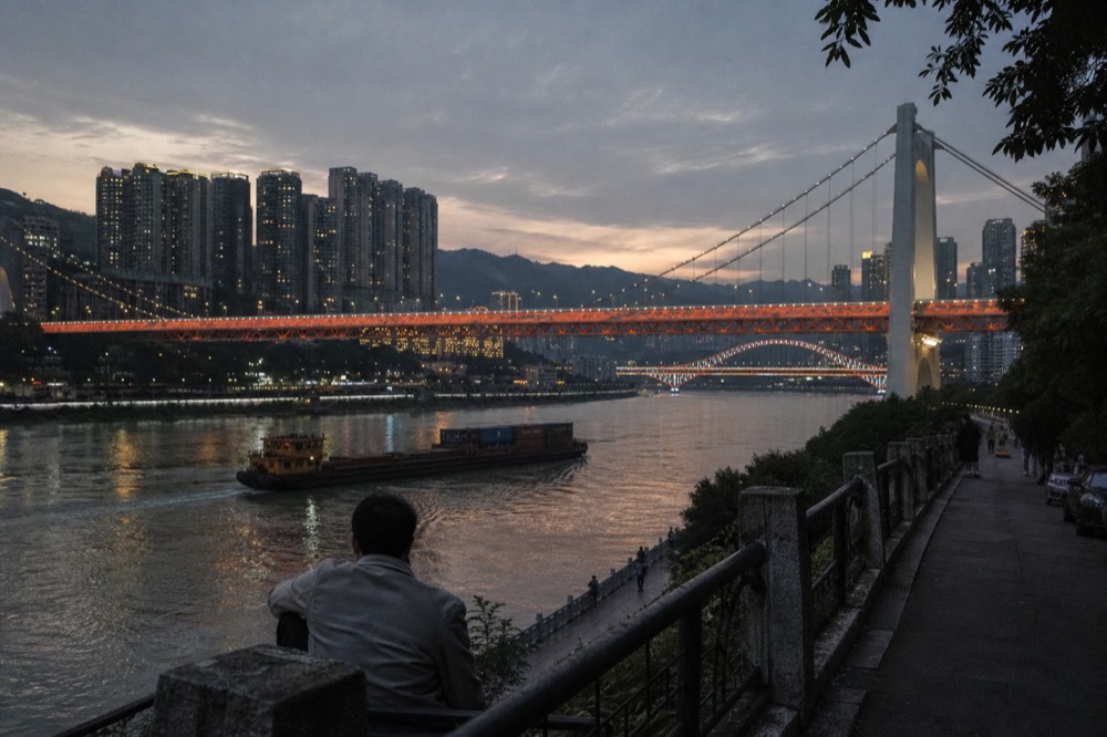 A wide river running through a densely built city at dusk with illuminated bridges crossing the water