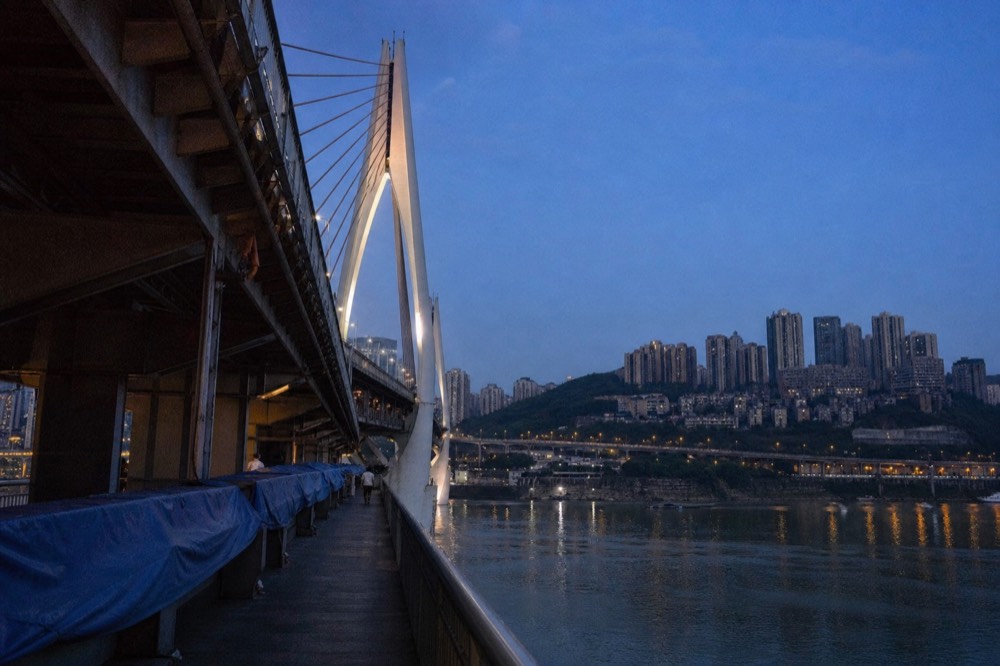 Bridge cables and tower lights against a deep blue evening sky