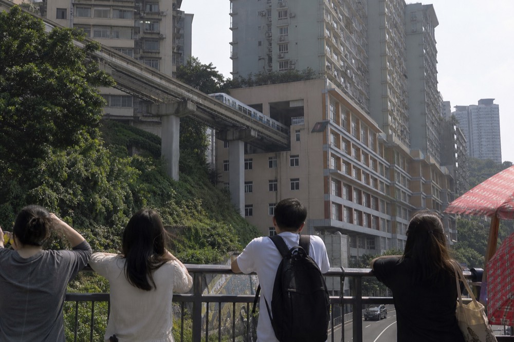 Monorail train passing through the mid-levels of a residential building above a viewing platform