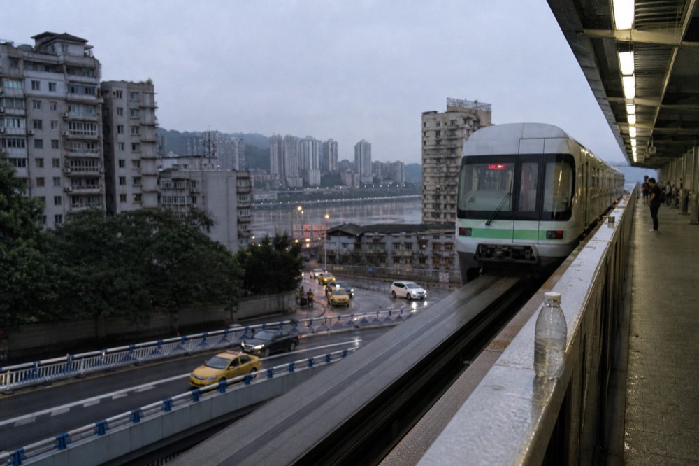Modern metro platform with train arriving in an elevated station above city streets