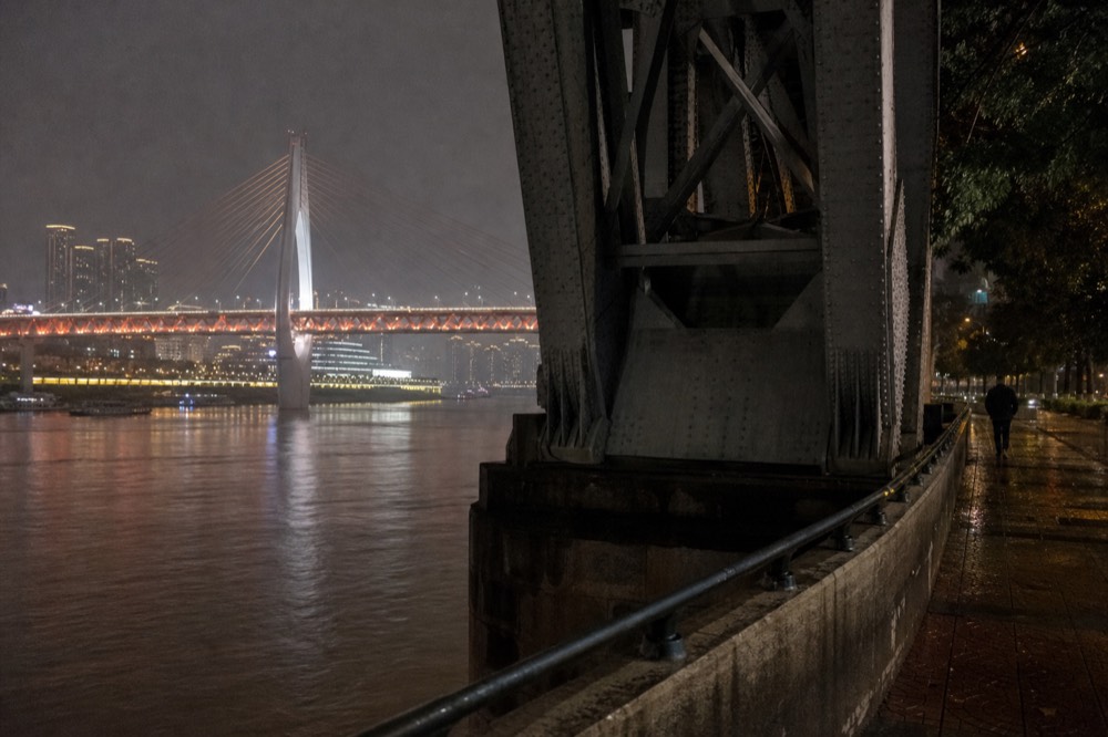 Illuminated bridge spanning a river at night with towers glowing on the far bank