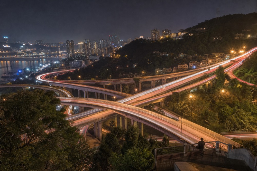 High aerial view of a stacked highway interchange with curving overpasses above the river in Chongqing.