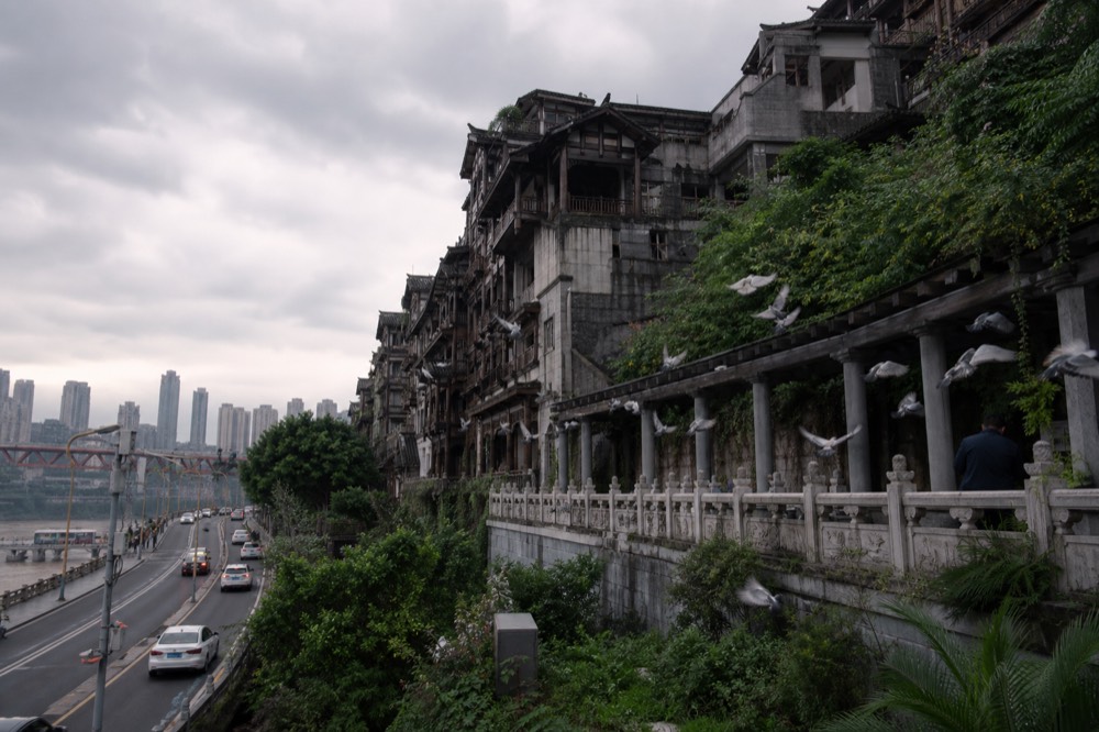 Timber balconies of a stilt-house complex stacked against a cliff beside a river