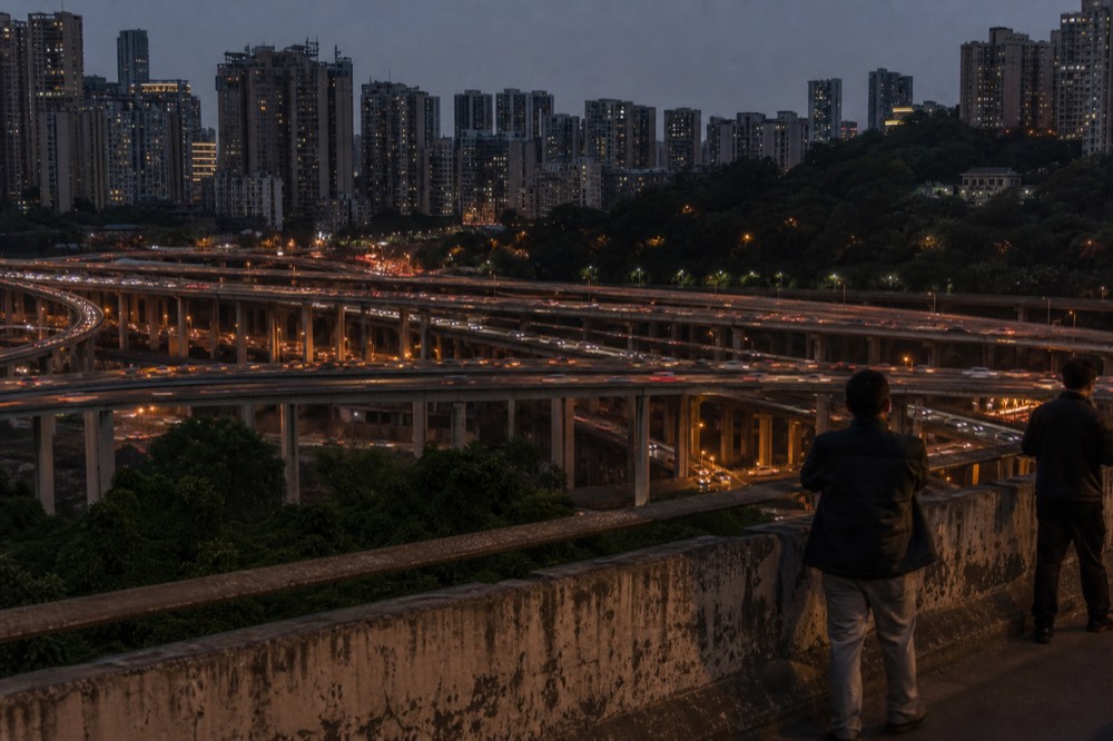 Layered city streets and bridges stacked across a hillside at dusk
