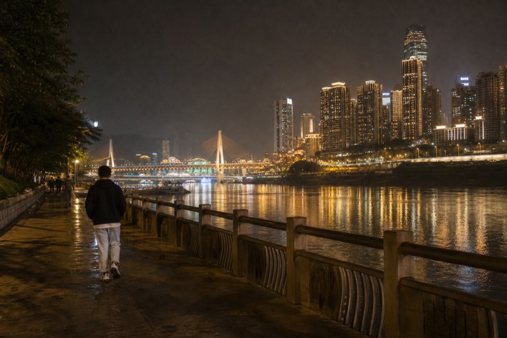 City towers and bridges illuminated in warm light reflected in a dark river at night