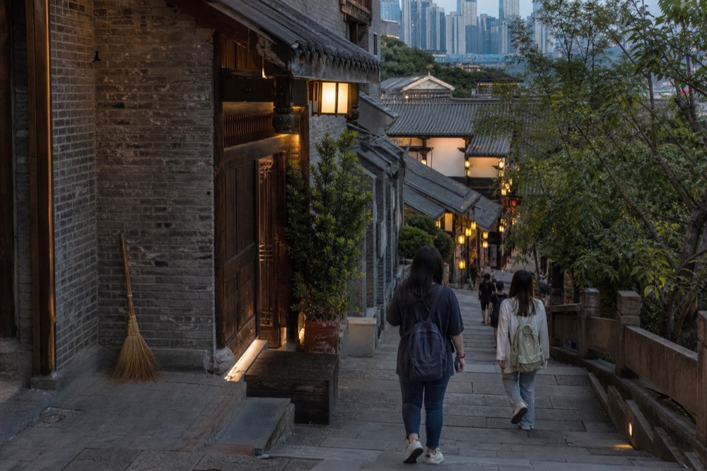 Pedestrians on a hilly stepped street between tall buildings in the evening