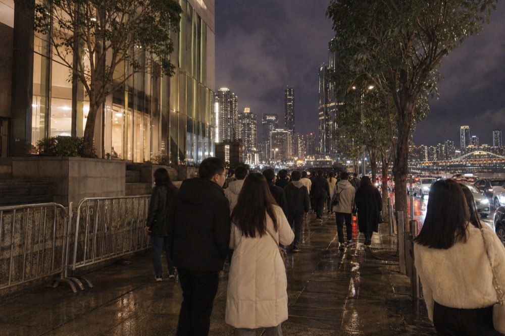 Dense pedestrian riverfront promenade at night in a central city district