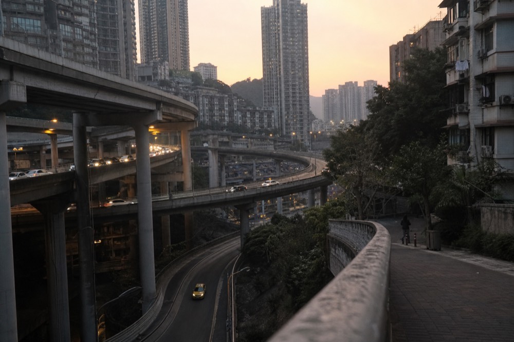 Stack interchange of multi-level roads between hillside residential towers at amber dusk
